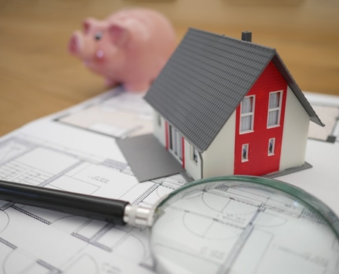 bank, tiny house, and magnifying glass signifying buying vs. renting in 2021